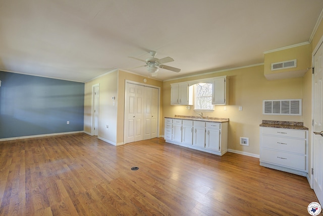 unfurnished bedroom with crown molding, visible vents, a sink, and wood finished floors
