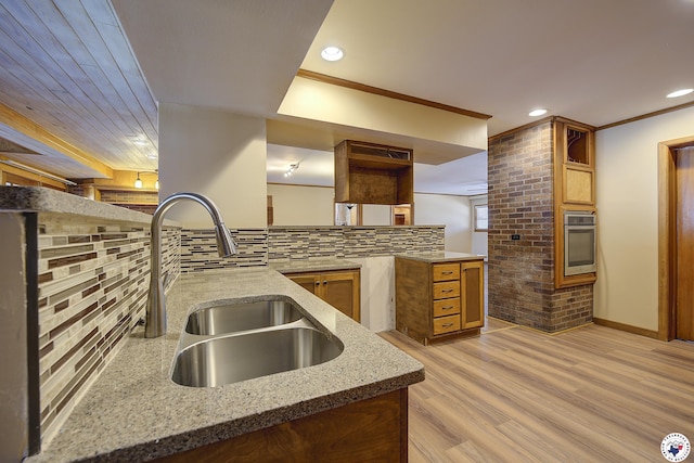 kitchen featuring light stone countertops, a sink, stainless steel oven, recessed lighting, and light wood-type flooring
