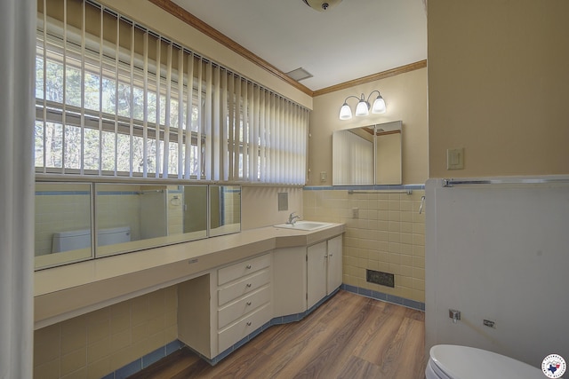 bathroom with tile walls, wood finished floors, a wainscoted wall, toilet, and ornamental molding