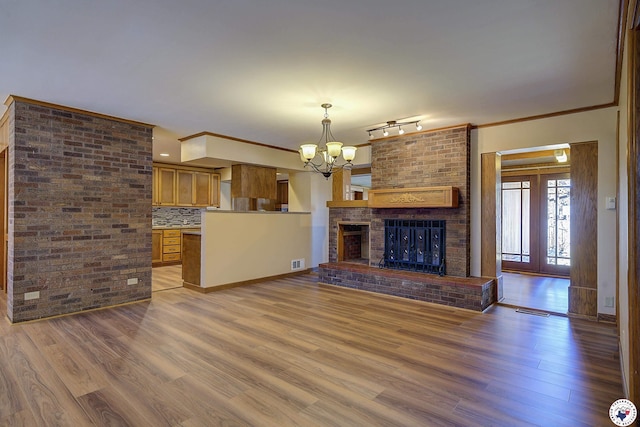 unfurnished living room with visible vents, wood finished floors, a chandelier, and a fireplace
