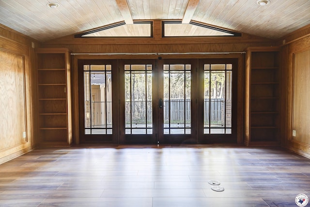 unfurnished room with wooden walls, built in shelves, french doors, and lofted ceiling
