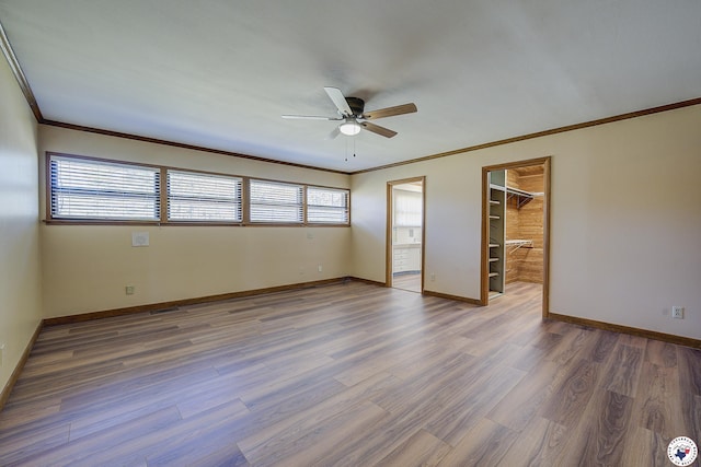 empty room featuring baseboards, a ceiling fan, wood finished floors, and ornamental molding