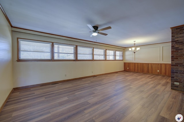 spare room featuring baseboards, ornamental molding, ceiling fan with notable chandelier, and wood finished floors