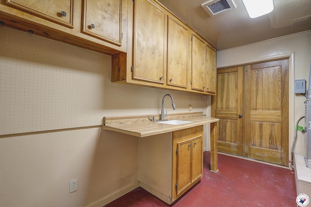 kitchen with visible vents, concrete flooring, a sink, light countertops, and baseboards