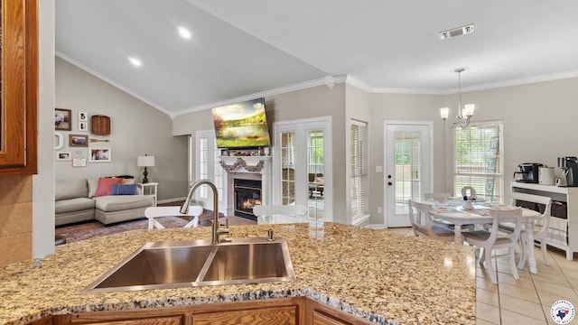 kitchen with light tile patterned flooring, open floor plan, a chandelier, light stone counters, and a sink