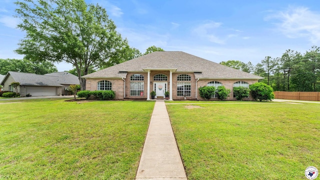view of front of property featuring roof with shingles, fence, brick siding, and a front yard