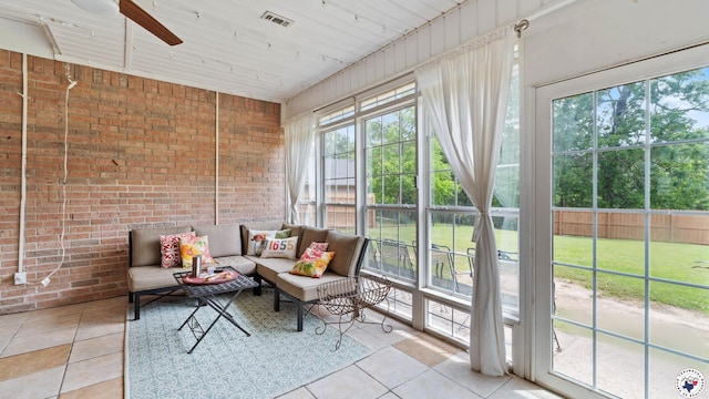 sunroom with brick wall, visible vents, plenty of natural light, and tile patterned flooring