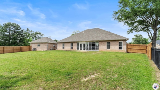 back of property with a lawn, a fenced backyard, and brick siding