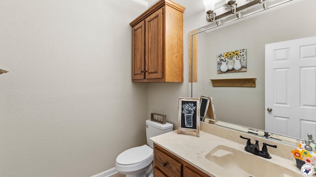half bathroom featuring toilet, baseboards, and vanity