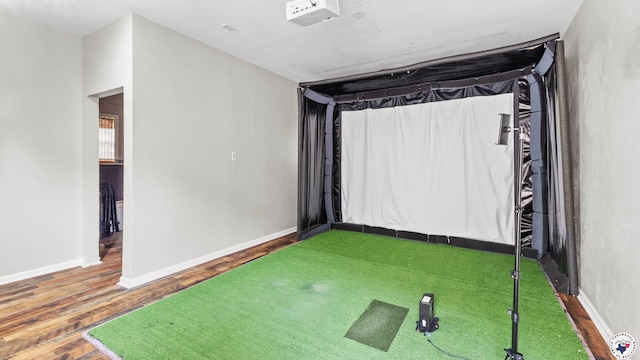 unfurnished room with baseboards, wood finished floors, and golf simulator