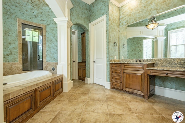 bathroom with decorative columns, wallpapered walls, a garden tub, and a wealth of natural light