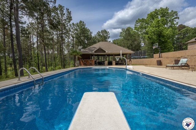 pool featuring fence, a diving board, and a patio area