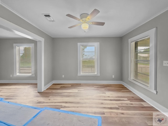 empty room featuring light wood-type flooring, ceiling fan, crown molding, and plenty of natural light