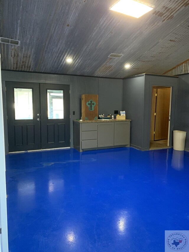 miscellaneous room featuring wooden ceiling, concrete flooring, and french doors