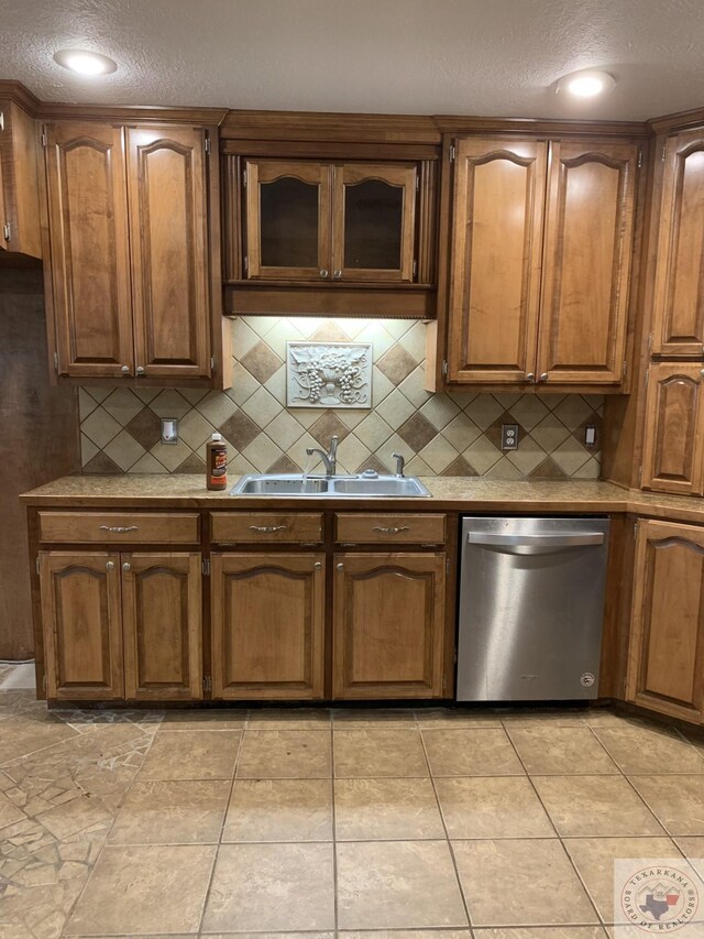 kitchen with sink, light tile patterned floors, dishwasher, and tasteful backsplash