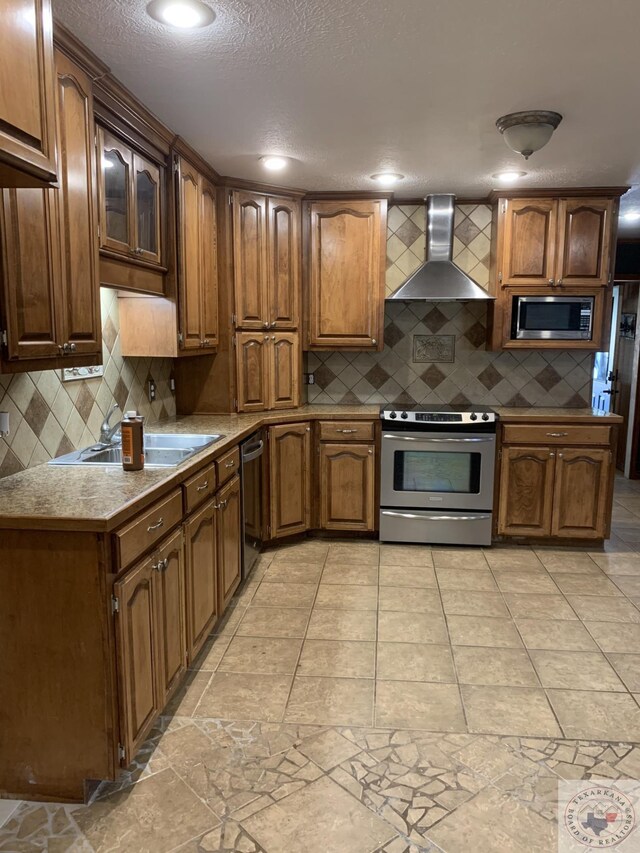 kitchen with sink, decorative backsplash, wall chimney exhaust hood, and appliances with stainless steel finishes