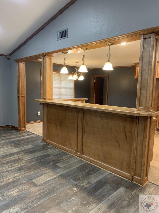 kitchen featuring decorative light fixtures, crown molding, dark hardwood / wood-style flooring, and lofted ceiling