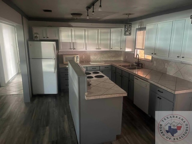 kitchen featuring pendant lighting, white appliances, dark hardwood / wood-style flooring, and sink