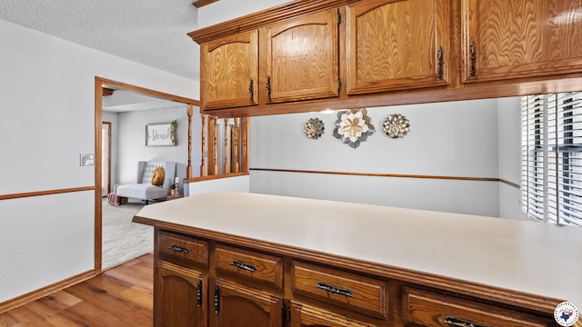 4707 Charleston St, Texarkana, AR 71854 - kitchen with light wood-style floors, brown cabinets, light countertops, a textured ceiling, and baseboards