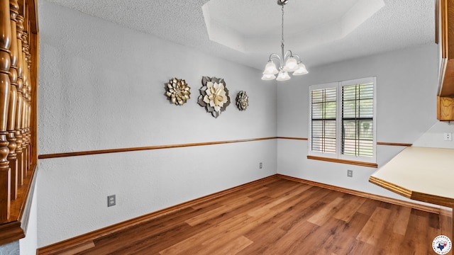 4707 Charleston St, Texarkana, AR 71854 - unfurnished dining area with wood finished floors, a textured wall, a chandelier, baseboards, and a textured ceiling