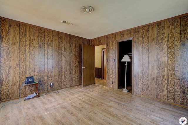 empty room featuring visible vents, wooden walls, and wood finished floors