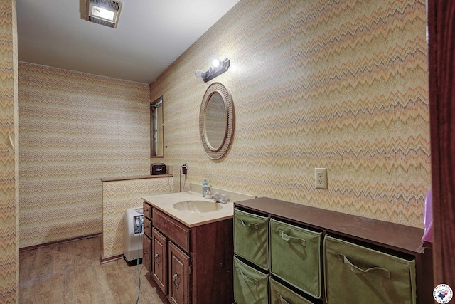bathroom with visible vents, wallpapered walls, wood finished floors, and vanity