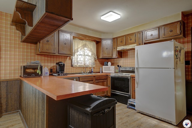 kitchen with light wood-style flooring, white appliances, a toaster, light countertops, and a peninsula