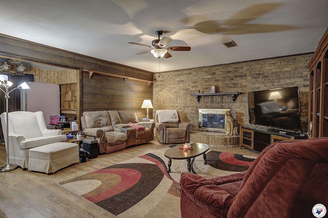 living room featuring wood finished floors, visible vents, a ceiling fan, and a brick fireplace