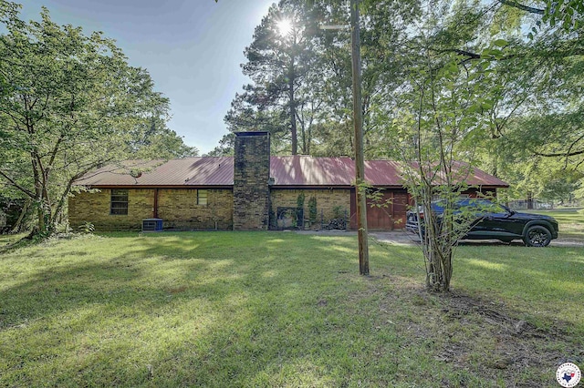 rear view of property featuring a yard, a chimney, and metal roof