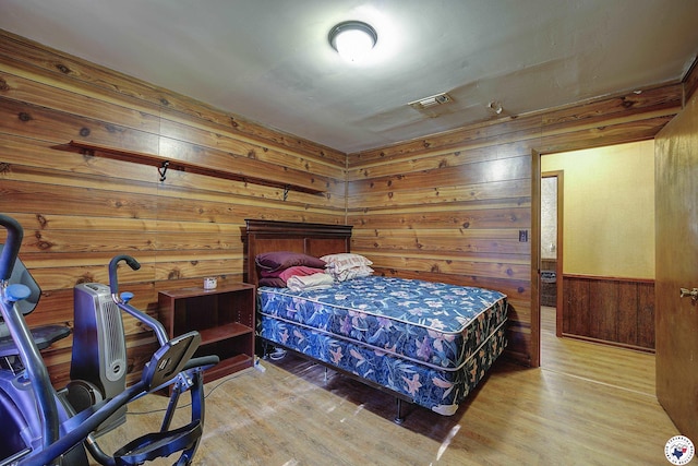 bedroom featuring wood finished floors, visible vents, and wood walls