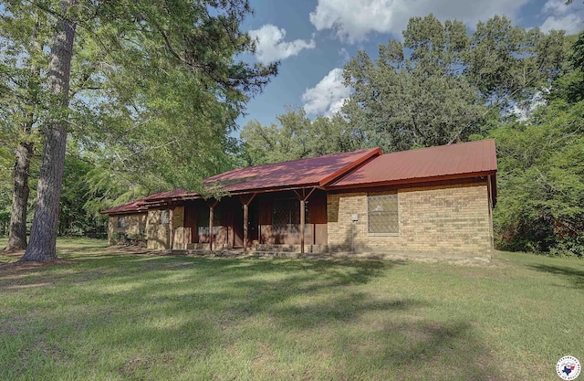 exterior space with brick siding, a front lawn, and metal roof