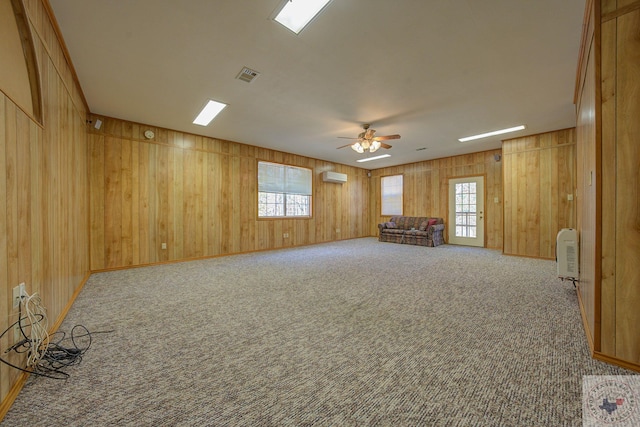 carpeted empty room featuring plenty of natural light, an AC wall unit, and ceiling fan