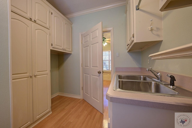 kitchen featuring sink, light wood-type flooring, and ornamental molding