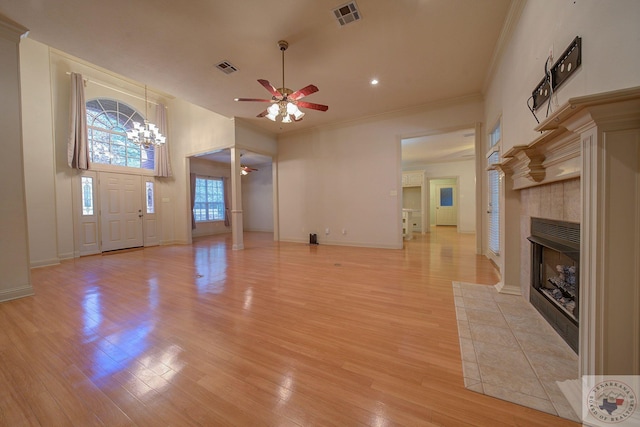 unfurnished living room featuring ceiling fan, light hardwood / wood-style floors, crown molding, and a tiled fireplace