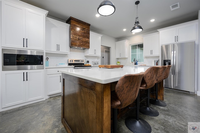 kitchen featuring appliances with stainless steel finishes, white cabinetry, sink, a kitchen island, and a breakfast bar