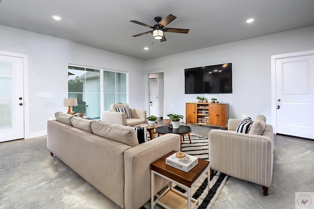 living room with a healthy amount of sunlight, concrete flooring, and ceiling fan