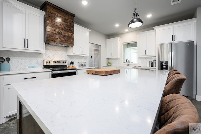 kitchen with a kitchen breakfast bar, white cabinetry, stainless steel appliances, and hanging light fixtures