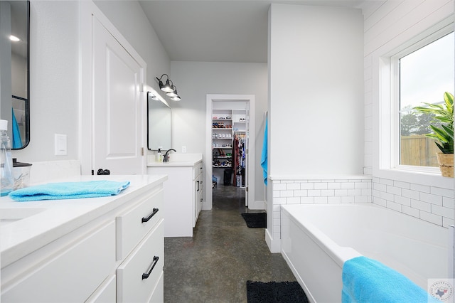 bathroom with a bathtub, vanity, and concrete flooring