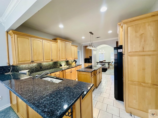 kitchen featuring black appliances, decorative light fixtures, light brown cabinets, sink, and kitchen peninsula