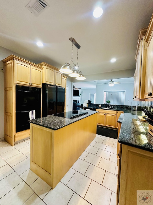 kitchen with sink, decorative light fixtures, dark stone counters, a kitchen island, and black appliances