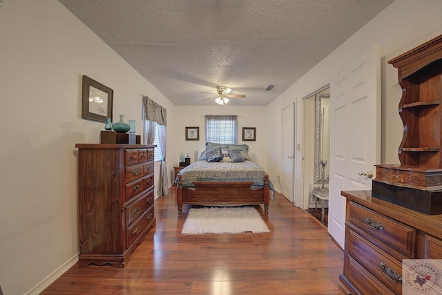 bedroom with ceiling fan, dark wood-type flooring, and a textured ceiling