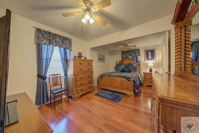 bedroom with ceiling fan, hardwood / wood-style floors, and a textured ceiling