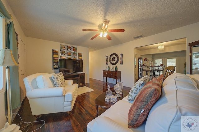 living room featuring ceiling fan, a textured ceiling, and dark hardwood / wood-style flooring