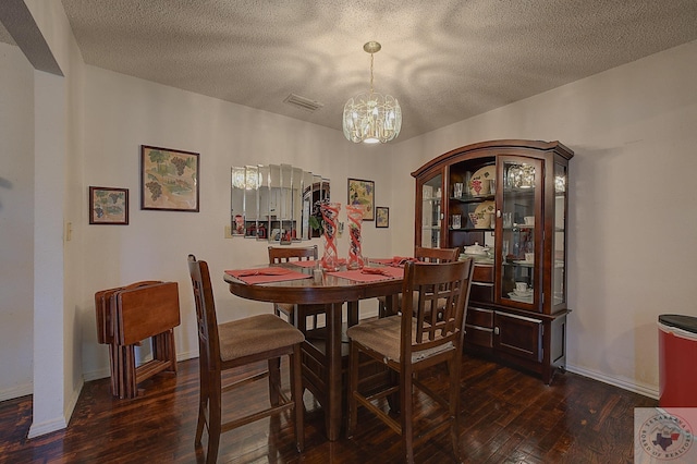 dining area featuring dark wood-type flooring, a textured ceiling, and an inviting chandelier