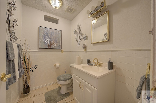 bathroom featuring toilet, tile walls, a textured ceiling, and tile patterned flooring