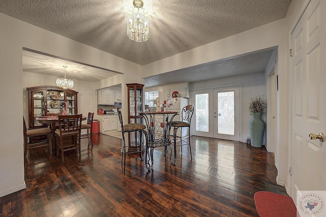 dining area with french doors, a chandelier, dark wood-type flooring, and a textured ceiling