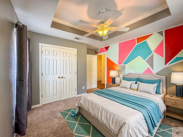 carpeted bedroom with ceiling fan, a tray ceiling, a closet, and crown molding