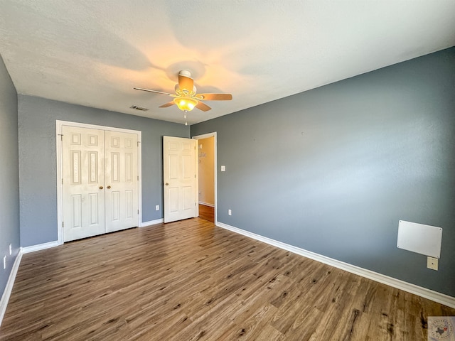 unfurnished bedroom with hardwood / wood-style floors, a closet, and ceiling fan