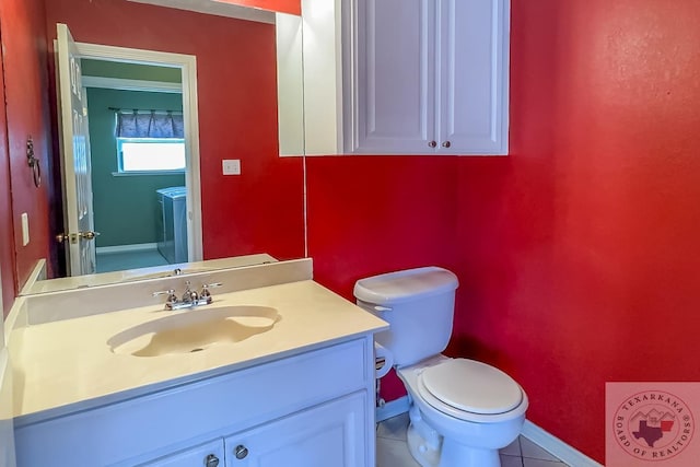 bathroom with toilet, vanity, and tile patterned flooring