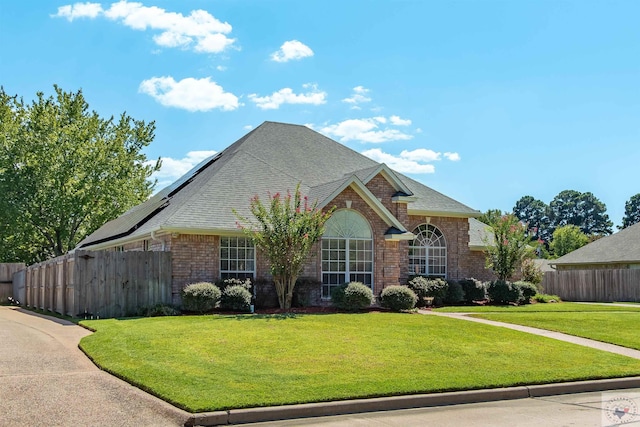 view of front of property with a front yard and solar panels